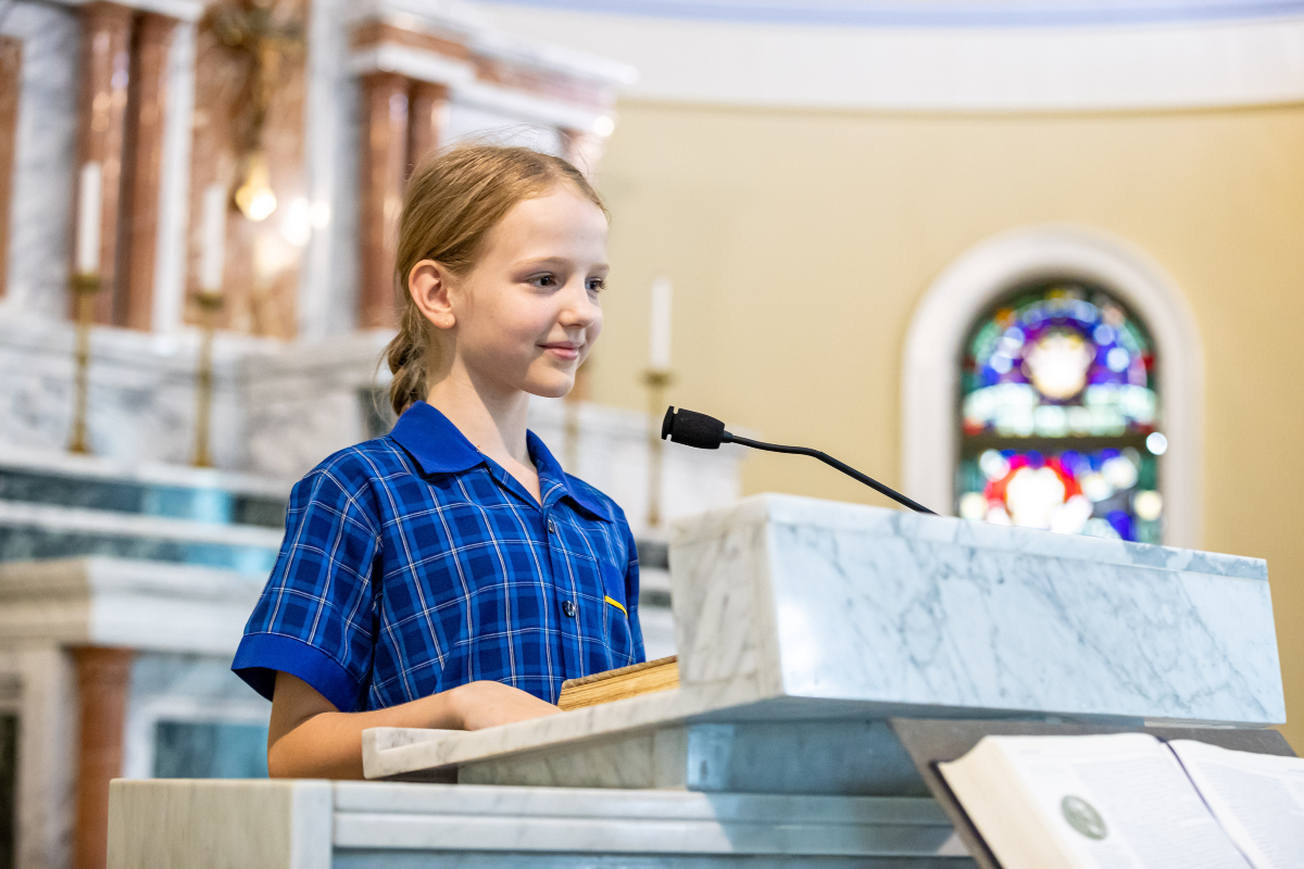 Student reading from a lectern during a church service, highlighting participation in liturgy, confidence and active faith expression at Holy Spirit School